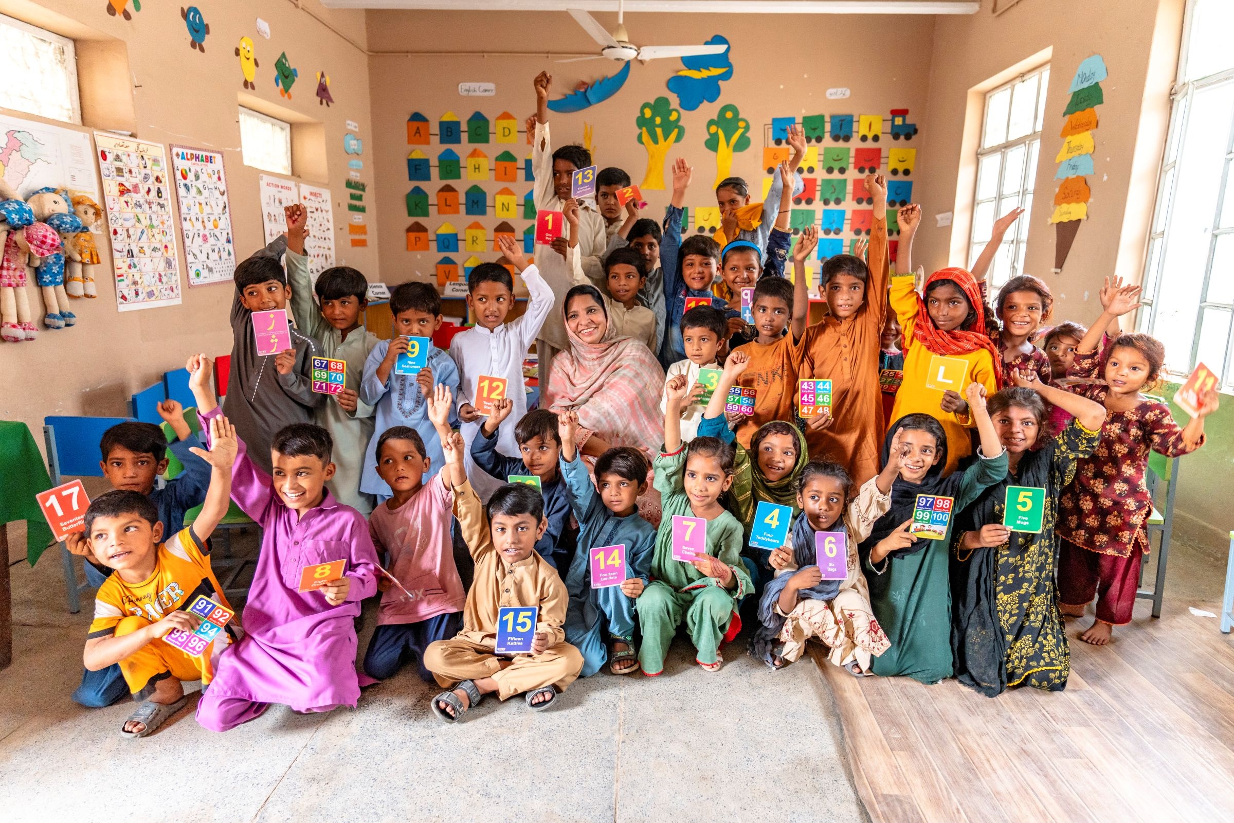 Students with their teacher, Shazia, at a foundational literacy and numeracy camp at Government Model Primary School, Lashkar, Bahawalpur.